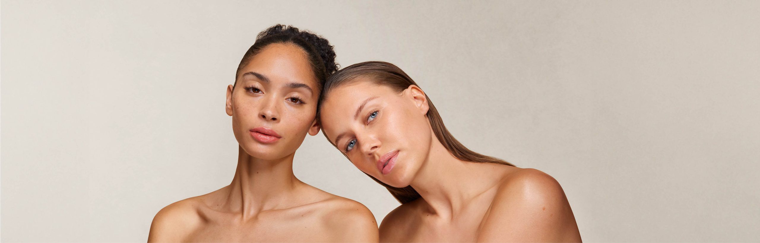 Zwei Frauen, eine lehnt den Kopf an die andere, beide schauen frontal.