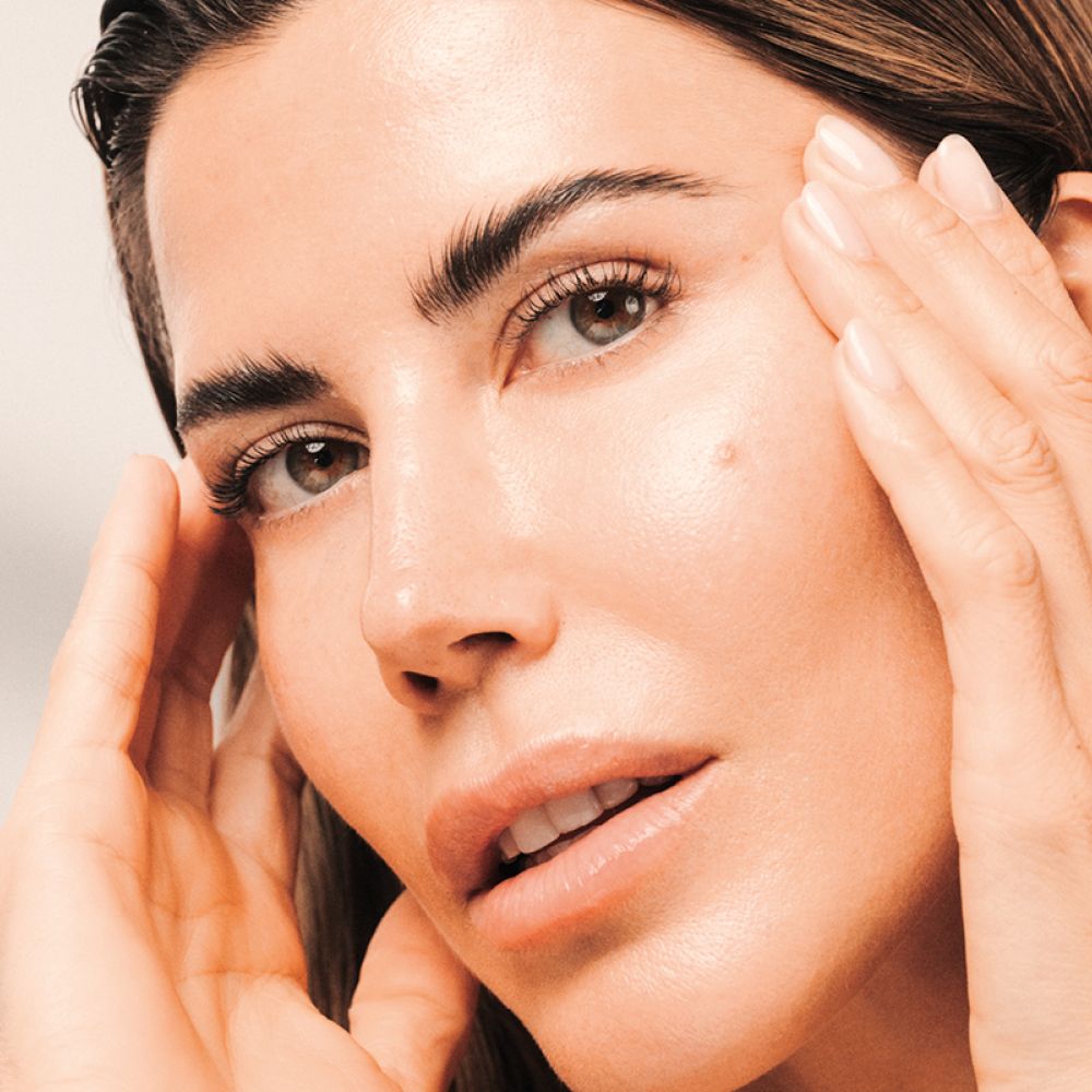 Frau mit strahlendem Hautbild berührt ihr Gesicht